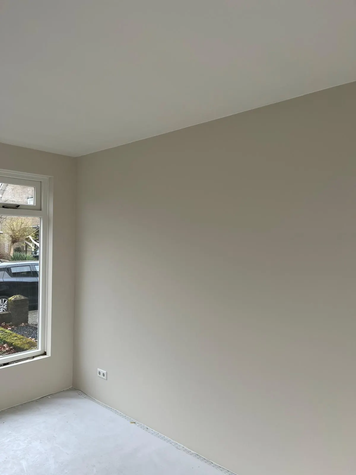 Een lichte kamer met egaal geschilderde zandkleurige wanden en een wit plafond.